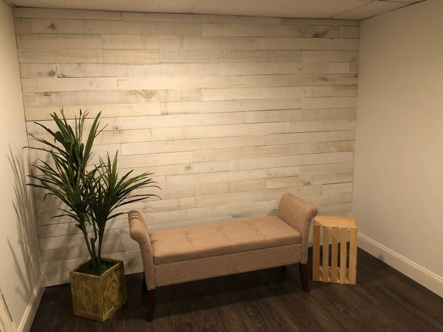 Whitewashed wood accent wall with bench in a finished basement