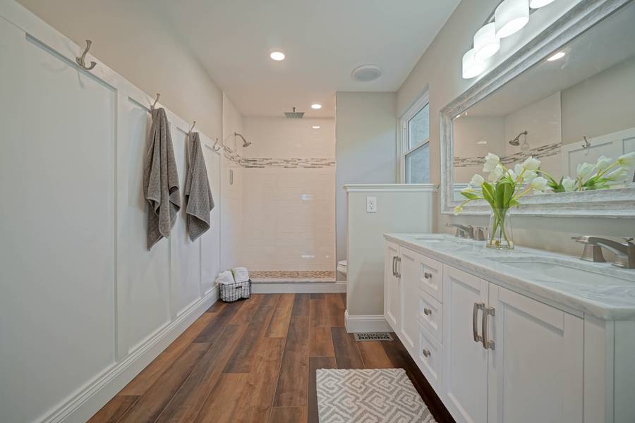 Renovated bathroom with white vanity and wood-look floor