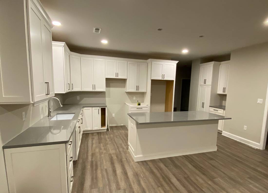 Renovated white kitchen with large island and wood-look flooring